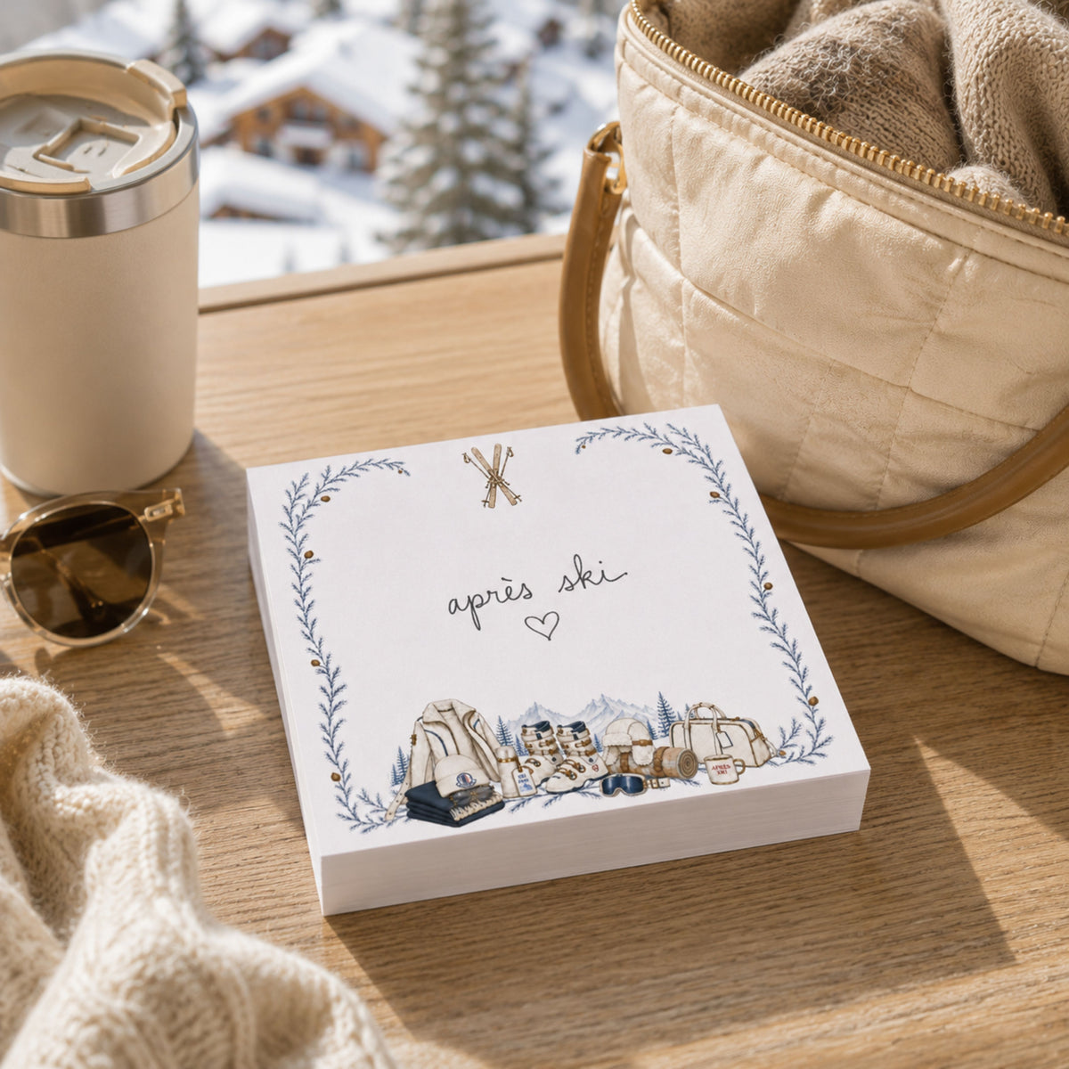 Proper Ski notepad on a wood table by a snowy chalet window with sunglasses and a sweater