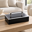 Black acrylic box with silver handle on an oak coffee table