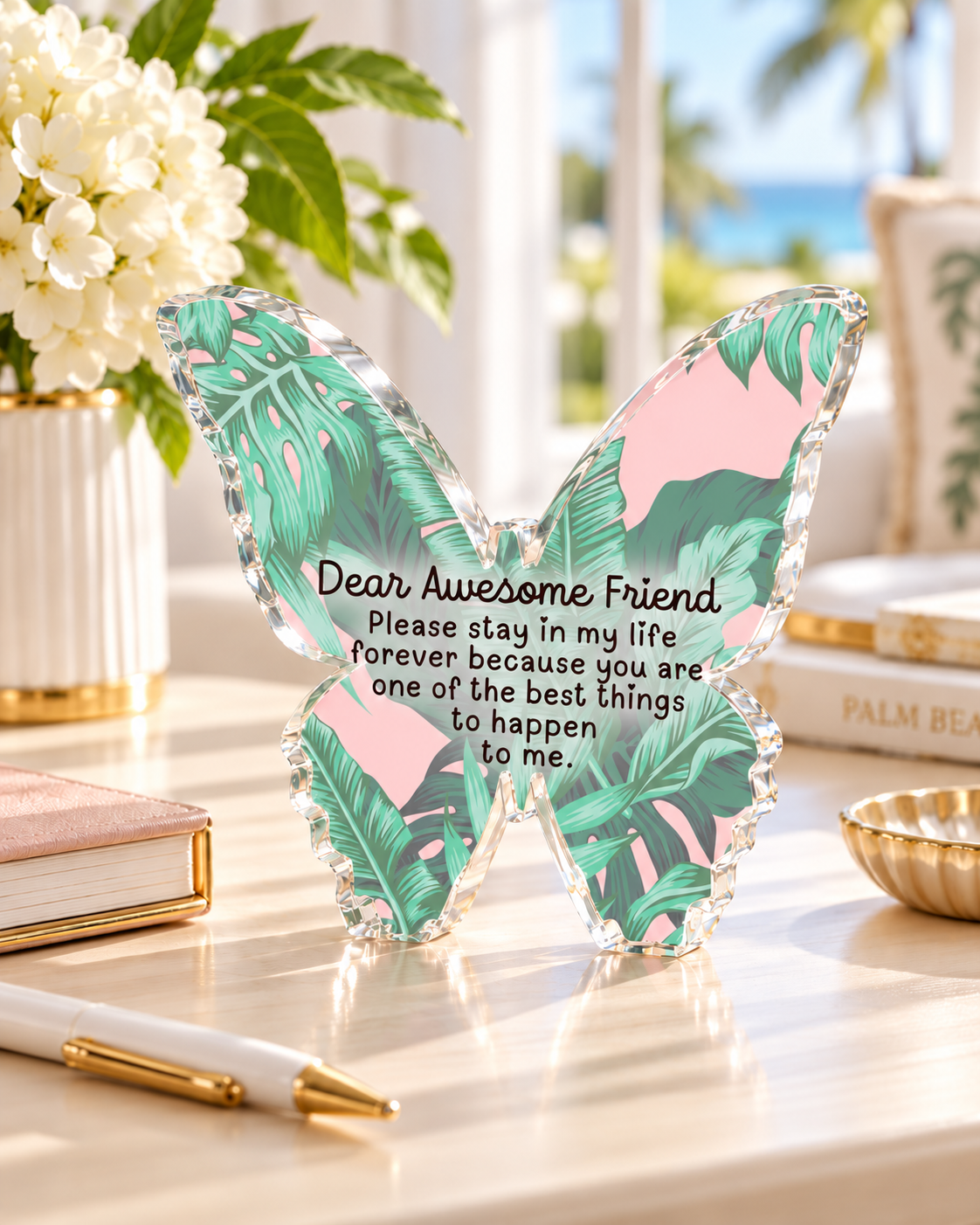 Awesome Friend acrylic butterfly desk weight on a desk beside white flowers and a gold pen