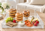 Bagels and donuts stacked on the dowels with fruit, crackers and dips in a living room