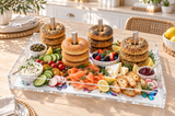 Bagel stacks on the dowels with smoked salmon, cucumber, radishes and dips on an outdoor dining table