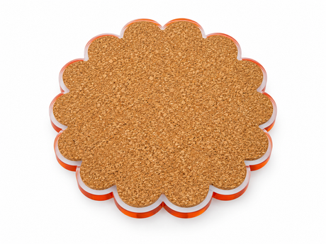 Cork back of a scalloped round coaster with an orange acrylic edge