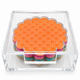 Orange cane coaster on top of a scalloped stack in a clear acrylic holder, front view