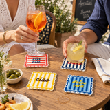 Guests holding spritz cocktails over the striped coasters on a wood table