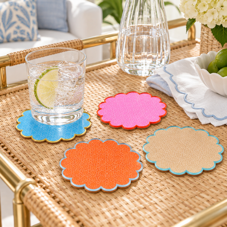 Pink, orange, blue and sand Cabana coasters spread across a rattan bar cart