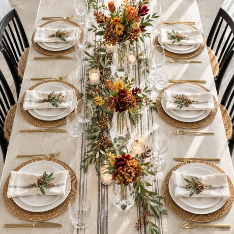 Overhead view of a fall dinner table with clear acrylic bud vases and autumn florals along the runner