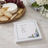 Hydrangea notepad with a handwritten cheese board list beside brie, crackers and grapes
