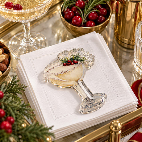 Festive Cocktail acrylic napkin weight on white cocktail napkins with champagne, cranberries and holiday greenery