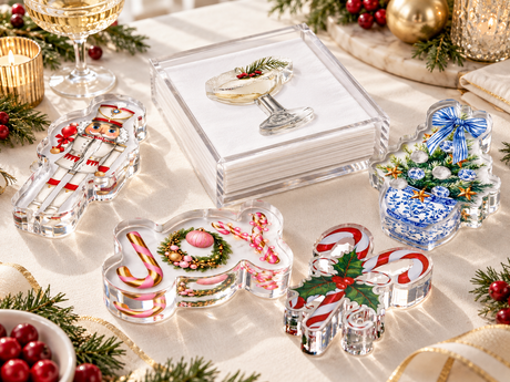 JOY acrylic napkin weight with nutcracker, candy cane and blue-and-white ginger jar napkin weights and a champagne glass napkin holder on a festive holiday table