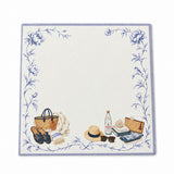 Front view of the Proper Beach Club 5x5 notepad with a lavender border, blue florals, a straw tote and sun hat