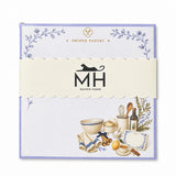 Proper Pantry 5x5 notepad wrapped in its scalloped MH band, with a mixing bowl, olive oil, lemon and recipe card