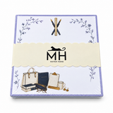 Proper Teacher notepad in its MH band with crossed pens and a ruler, books, a clipboard and a tote