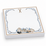 Proper Ski 5x5 notepad with a blank page, crossed skis, a gold border, blue pine vines and ski gear, angled view