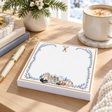 Proper Ski 5x5 notepad on a wood desk with a gold pen, pine branches, a frothy latte and a snowy window